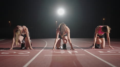 Front-view-zoom-camera-three-women-in-the-stadium-at-night-in-slow-motion-start-and-run-to-the-camera